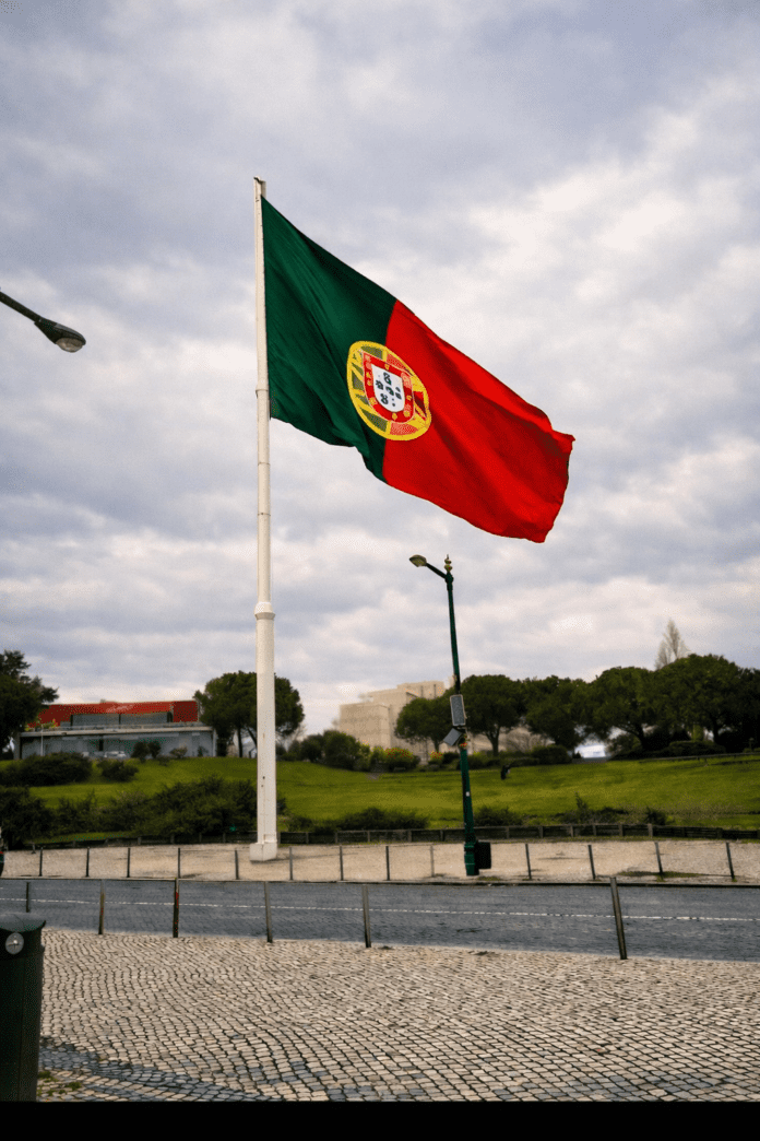 Portuguese flag flying in Lisbon under a cloudy winter sky, symbolizing arrival and the start of a week working remotely in Portugal.